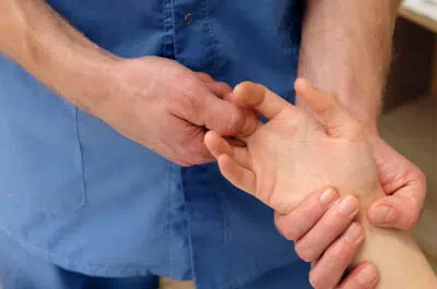 Mains d'un kiné tenant la main d'un patient – fracture des phalanges | IK Kiné et Balnéo Paris