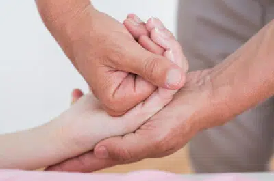 Mains d'un kiné rééduquant les doigts d'un patient – luxation des doigts | IK Kiné et Balnéo