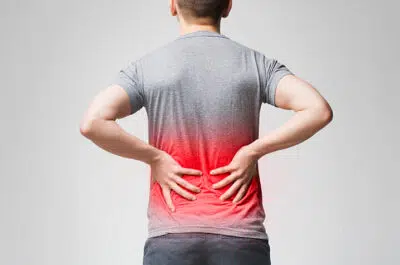 Homme se tenant le bas du dos, zone douloureuse en rouge – sciatique du sportif | IK