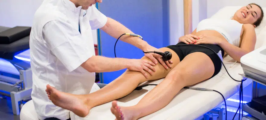 Kinesitherapeute soignant le genou d une jeune femme allongee sur son ventre | IK Paris
