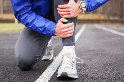 Coureur se tenant le genou sur la route – fracture des plateaux tibiaux | IK Kiné et Balnéo