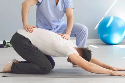 Kinesitherapeute aidant un patient a faire des exercices pour son dos - lyse isthmique| IK Paris