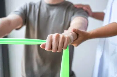 Bras tirant un élastique vert – traumatologie du sport et suivi par un kiné | IK Kiné et Balnéo