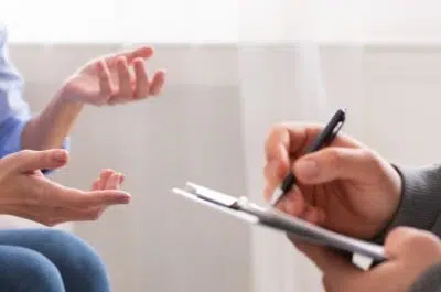 Patient échangeant avec un kiné qui prend des notes – reconnaître un bon kiné | IK