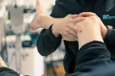 Kinésithérapeute tenant le genou d'un patient – douleurs aux genoux | IK Kiné et Balnéo Paris