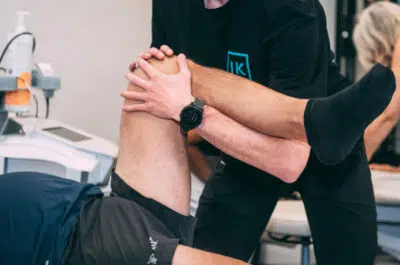 Kiné étirant la jambe d'un patient – douleur au genou, quand consulter | IK Kiné et Balnéo
